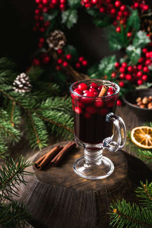 Mulled wine with cranberries and cinnamon in glass on wooden board. Hot Christmas drink, still life. Selective focusの写真素材