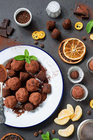 Dark chocolate truffles with orange peel on white plate over dark stone background. Top viewの写真素材