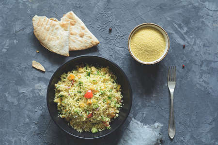 Tabbouleh with cous cous and arabic flatbread on concrete background. Healthy dietetic meal. Table...