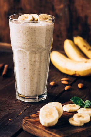 Banana smoothie in glass on brown wooden table. Healthy food, healthy eating conceptの写真素材