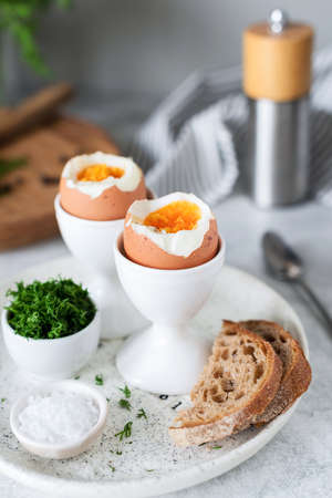Soft boiled eggs and toasts for breakfast served with sea salt and chopped dill. Selective focus
