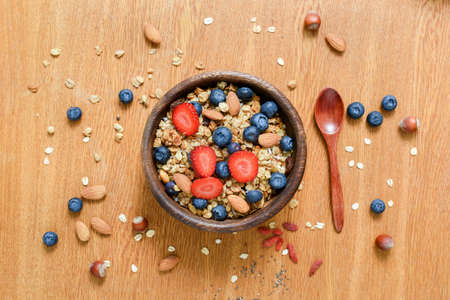 Granola bowl with fresh strawberries and blueberries on wooden table. Flat lay, concept of healthy lifestyle, healthy eating, dieting and balanced mealの写真素材