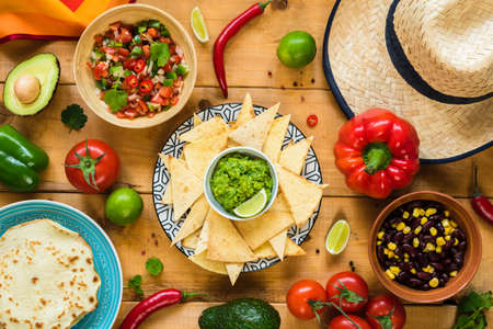 Traditional Mexican food on wooden table. Tortilla chips, guacamole, nachos, beans and salsa. Table top viewの写真素材