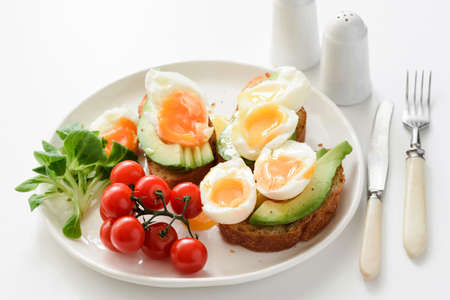 Egg and avocado toasts on white plate, closeup view. Concept of healthy breakfast, healthy lifestyle, dieting, fitness, weight loss, vegan, vegetarianの写真素材