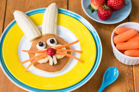 Funny healthy breakfast for kids on Easter. Easter bunny pancake on yellow plate. Closeup view, selective focusの写真素材