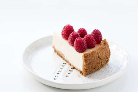 Isolated Slice of Cheesecake with fresh raspberries on white plateの写真素材