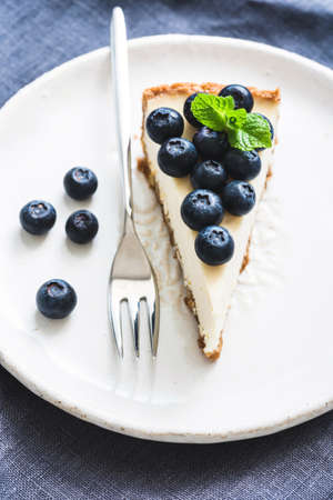 Cheesecake with fresh blueberries on white plate, selective focus, vertical compositionの写真素材