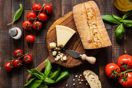 Italian food Parmesan cheese, Ciabatta bread, Bruschetta, Tomatoes and Basil on Rustic Wood Background. Top viewの写真素材