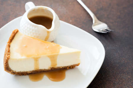Cheesecake with caramel sauce on white plate, closeup view, selective focusの写真素材