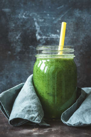 Detox green smoothie in bottle glass with drinking straw. Kale spinach green smoothie. Smoothie bottle. Cleansing, detox, diet, fitness, healthy lifestyle conceptの写真素材