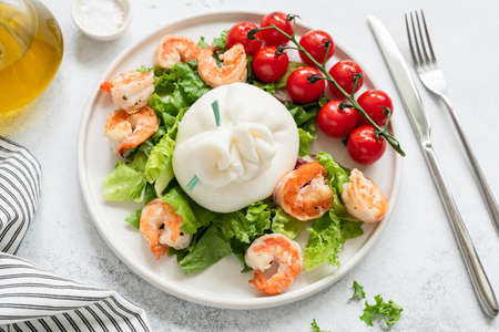 Burrata salad with shrimps, lettuce, tomatoes and olive oil on a white plate. Closeup view. Healthy italian saladの写真素材