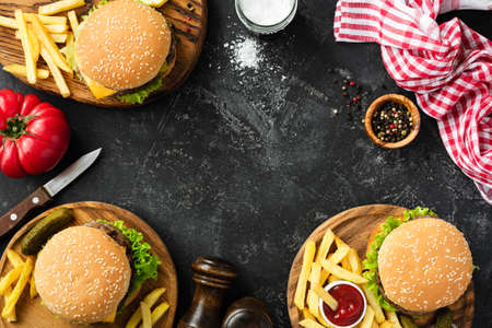 Burgers and french fries on dark stone background, top view with copy space. Homemade hamburgers and fries. Fast food or BBQ conceptの写真素材