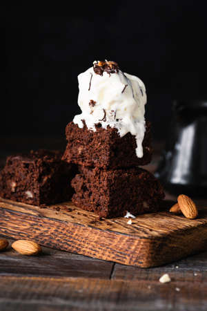 Chocolate brownies with vanilla ice cream on black background. Closeup view, selective focus