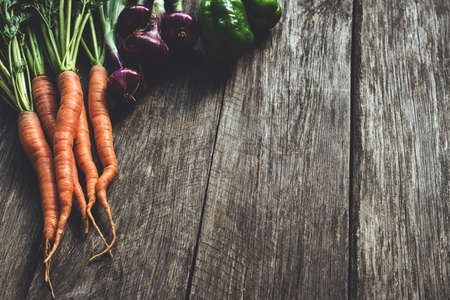 Fresh vegetables on wooden planks. Carrots, cucumbers and purple onions on old wooden table. Farmer market. Selection of bio organic root vegetablesの写真素材
