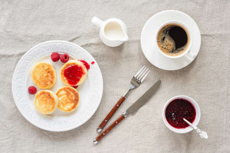 Cottage cheese pancakes with raspberry jam and coffee. Top view. Syrniki or sirniki, russian cuisine farmers cheese fritters or pancakesの写真素材