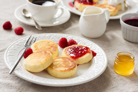 Breakfast table with cottage cheese pancakes, honey, jam and coffee. Closeup view, selective focusの写真素材