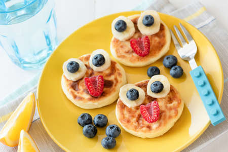 Fun food for kids. Pancakes with funny animal faces on colorful yellow plate. Kids meal. Selective focusの写真素材