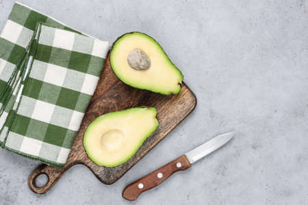 Avocado halved on wooden cutting board. Top view, copy space for text