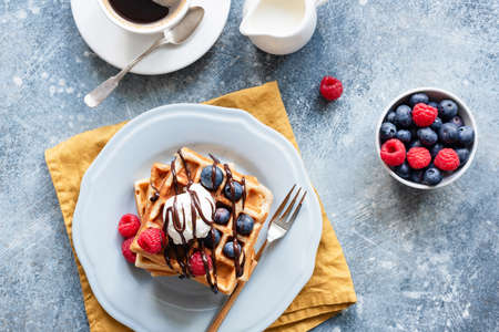 Breakfast with belgian waffles and coffee. Waffles served with berries, ice cream and chocolate...
