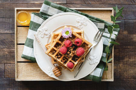 Belgian waffles with honey and raspberries for breakfast. Waffles decorated with flower, berries,...