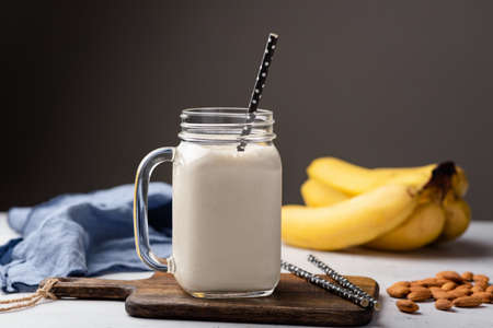 Banana protein smoothie or milkshake in drinking glass over dark gray background, copy space for textの写真素材