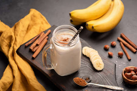 Banana smoothie with cinnamon in drinking glass on dark background. Selective focusの写真素材