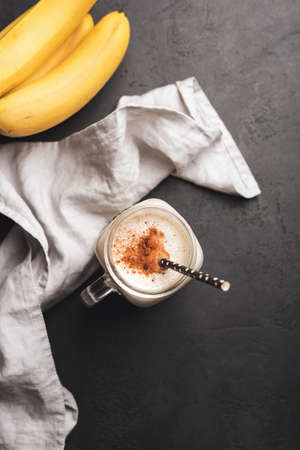 Banana cinnamon protein smoothie on black concrete background. Top view, copy space for text,...
