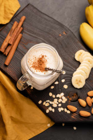 Banana milkshake or protein smoothie drink with cinnamon and oats. Top view, selective focusの写真素材