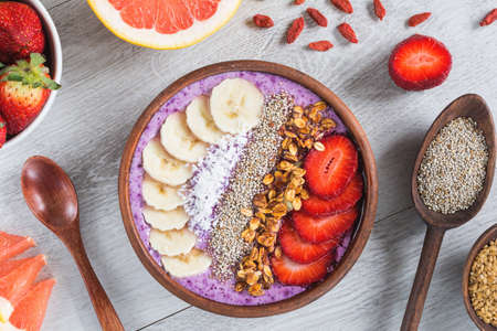 Acai smoothie bowl with superfoods. Smoothy bowl topped with banana, chia seed, coconut, strawberry and granolaの写真素材