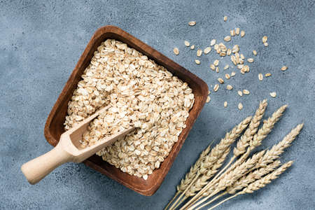 Rolled oats in wooden bowl on concrete background, top view. Concept of healthy eating, agriculture,...