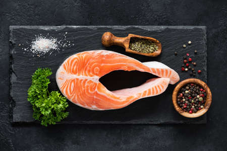 Raw salmon steak and spices on slate ready for cooking, top view. Healthy eating, paleo diet conceptの写真素材