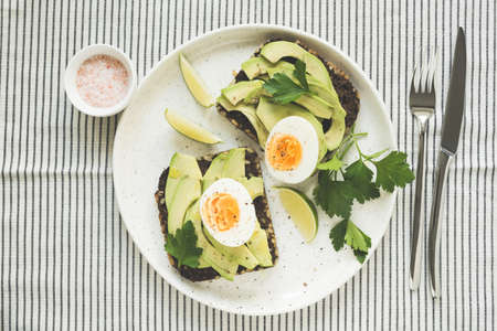 Avocado and egg on rye bread on a plate on textile, top view. Healthy breakfast, healthy eating or...