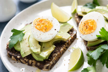 Whole grain rye toast with avocado and egg garnished with parsley. Healthy snack, breakfast or lunch