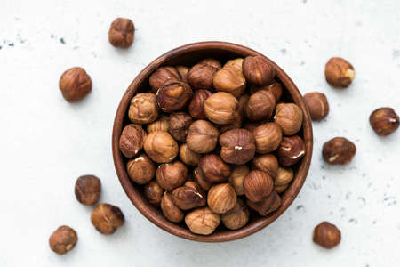 Hazelnuts in bowl. Unpeeled hazelnuts in wooden bowl on white background