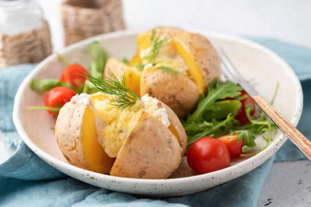 Stuffed potatoes baked with cheese, sour cream and dill. Closeup view, selective focusの写真素材