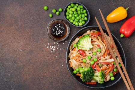 Noodles stir fry with vegetables. Udon noodles with broccoli, green pea, carrot, pepper and teriyaki sauceの写真素材