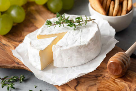 Tasty Brie Cheese or Camembert Cheese On Olive Wooden Serving Board. Closeup viewの写真素材