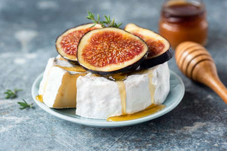 Brie or camembert cheese with fig and honey on plate. Tasty white cheese closeup viewの写真素材