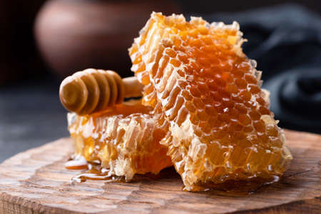 Honeycomb and honey dipper on wooden board. Selective focus. Raw honey, Natural honeyの写真素材