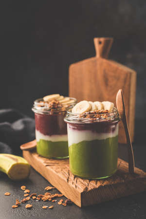 Rainbow smoothie in jar for breakfast. Healthy detox vegan smoothie or parfait topped with granola and bananaの写真素材