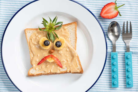 Toast with funny face for kids. Angry Bird face on peanut butter toast, kids breakfast