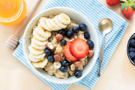 Healthy Oatmeal Porridge Bowl With Berries, Fruits On Blue Napkin. Table Top Viewの写真素材
