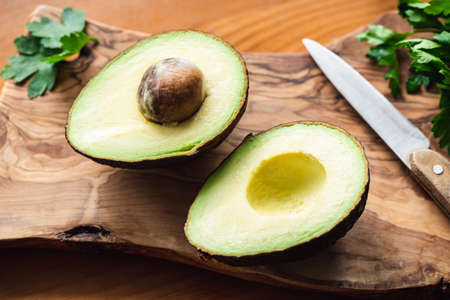Two avocado halves on wooden cutting board, closeup view. Concept of healthy food, healthy eating