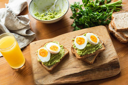 Toast with avocado and egg for healthy breakfast on wooden table. Top view