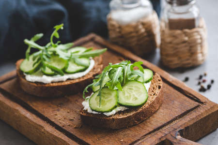 Healthy sandwich with cucumber and cream cheese on wooden cutting board. Closeup view, selective focusの写真素材