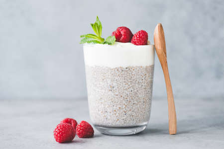 Chia pudding parfait with yogurt and raspberries in a glass. Grey concrete texture backgroundの写真素材