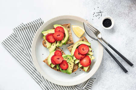 Avocado strawberry toast on a plate. Table top view on concreteの写真素材