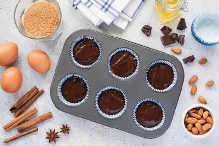 Homemade cupcakes or muffins dough in baking tin. Preparation of sweet chocolate pastry. Baking...