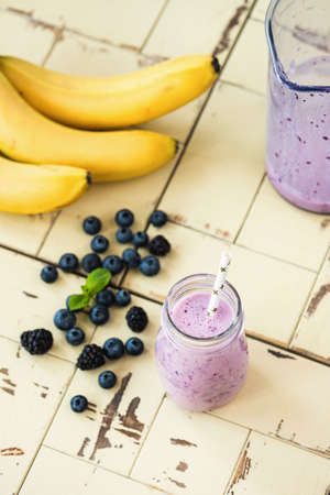 Tasty blueberry smoothie in bottle on textured woodenの写真素材