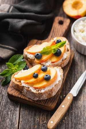 Bruschetta with ricotta cheese, peach and blueberries on woodenの写真素材